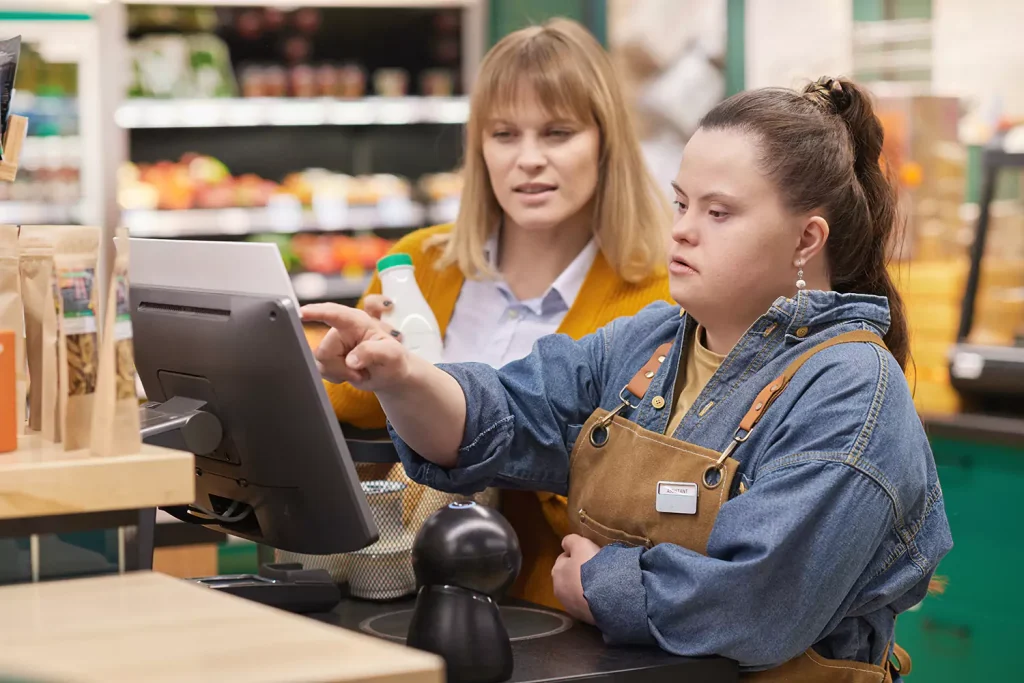 Disabled woman with down syndrome at cashier with support worker