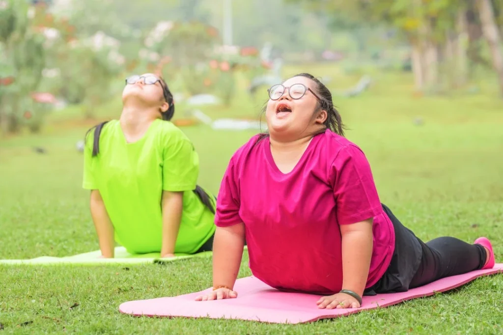 Two disabled friends with down syndrome in park on yoga mats stretching